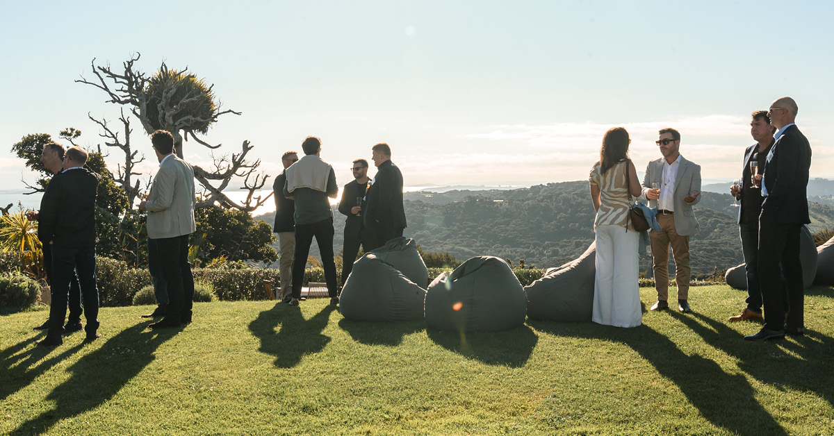 Corporate guests networking at an outdoor event on Waiheke Island at golden hour